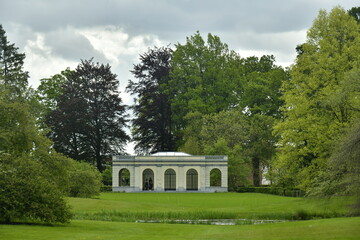 Fototapeta na wymiar Le pavillon d'été et la végétation luxuriante verte contrastant avec le gris des nuages à l'arboretum de Wespelaar en Brabant Flamand 
