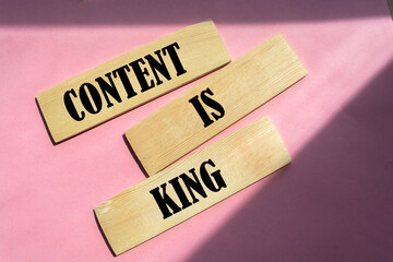 word content is king on wooden block on pink background.