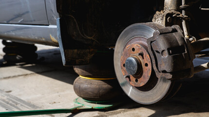 Fototapeta premium Car repair. Car with removed wheels on pneumatic jacks. View of the brake discs hub.