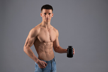 Gain mass. Muscular guy hold bottle of dietary supplemets. Sports nutrition supplements
