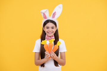 Obraz na płótnie Canvas happy easter kid girl in bunny ears and bow tie hold carrot, happy easter
