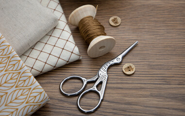 A spool of thread, scissors, and cotton cloths on the table