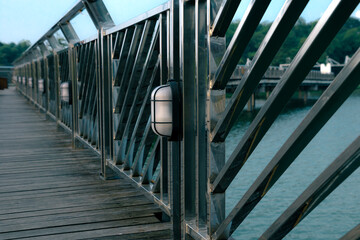 Metal bridge with lampposts against a tranquil waterfront. Lamp posts on a steel bridge with a calm...