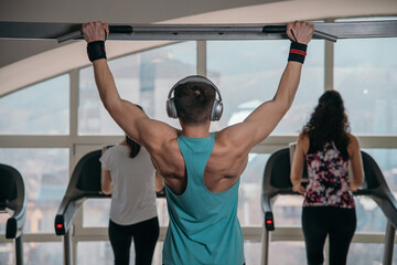 Handsome athlete working out at gym. Pull ups, exercising back. Fitness people.