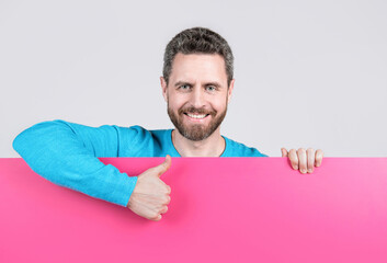 happy man behind blank paper banner with copy space for job offer show thumb up, proposition.