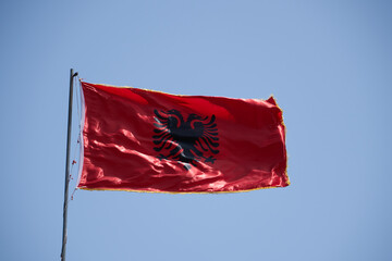 Albania flag waving against clean blue sky, close up, isolated with clipping mask alpha channel transparency, perfect for film, news, digital composition - Powered by Adobe