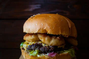 juicy burger with beef cutlet, sauce and vegetables, on a blurred background from the boards