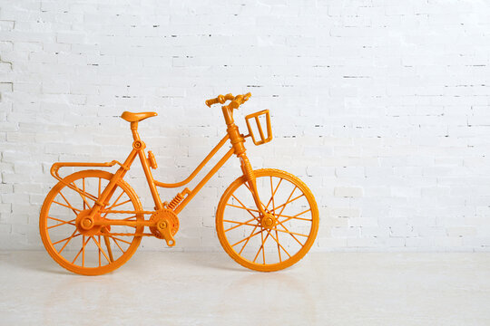 The vintage yellow bicycle parking against white brick wall