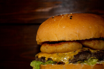 juicy burger with beef cutlet, sauce and vegetables, on a blurred background from the boards