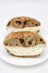 New York City Cinnamon Raisin Bagel Halves filled with Cream Cheese on a White Plate