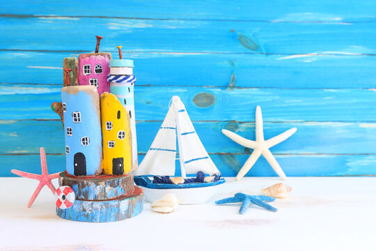 Nautical concept with sea life style objects as boat, driftwood beach houses, seashells and starfish over wooden background