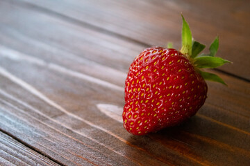 red, juicy strawberry berry lying on a wooden table