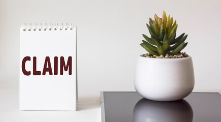 The word CLAIM is written on the pad. A cactus stands on a white and black background