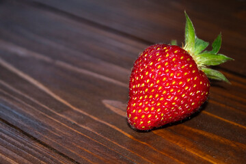 red, juicy strawberry berry lying on a wooden table
