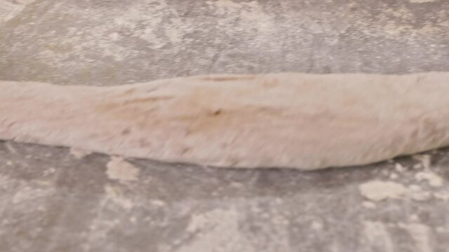 Female hamds make a baguette out of dough