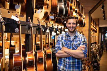 Portrait of professional seller standing in music shop and selling guitars instruments.