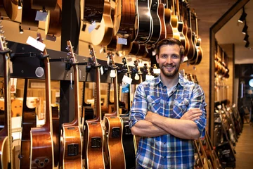 Foto op Plexiglas Muziekwinkel Portret van een professionele verkoper die in de muziekwinkel staat en gitareninstrumenten verkoopt.