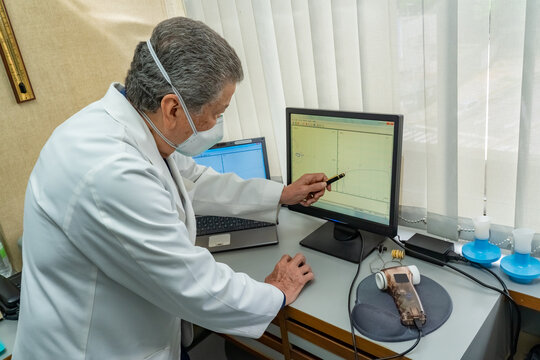Senior doctor looking the medical results at computer at doctor office
