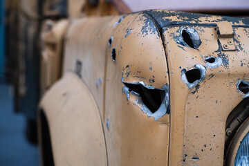 Bullet and shrapnel holes on the front of a yellow vehicle painted in desert camo colors. Concepts...