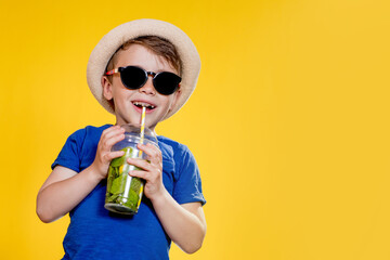 Cute boy Drink Mojito cocktail From Plastic Cup Over Yellow Studio Background