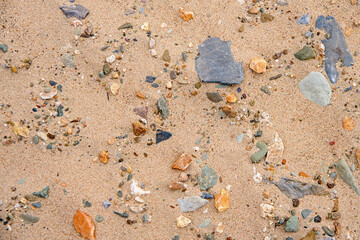 Background multicolored river pebbles, stones randomly lie on the sand 