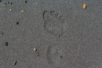 Summer background idea: footprint on a wet beach sand. Horizontal minimalistic wallpaper