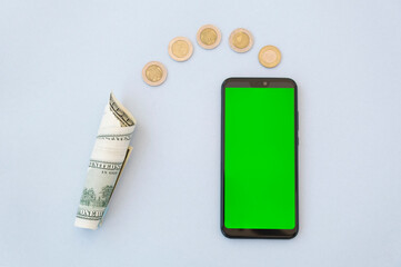 Phone with a green screen lies on a blue background with american money dollars