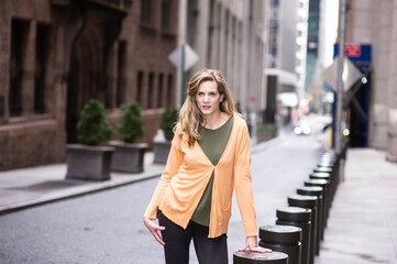 Fototapeta premium A young woman is standing on the street and looking forward. .