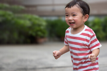 Portrait of an asian boy (toddler) running toward and smiling with happy and fun face while playing...