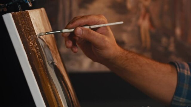 Man artist paints with brush strokes of black paint oil