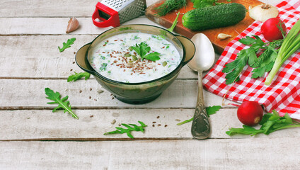 summer cold kefir soup in glass bowl with spicy herbs