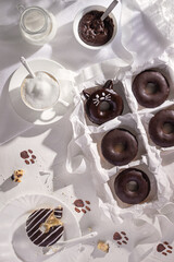 Glazed chocolate donuts and cup of cappuccino on stone background. Top view. Flat lay composition