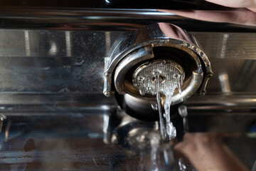 Close-up of the chrome parts of a professional coffee machine. Coffee maker in a cafe and water drops are falling.