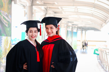 Portrait of two happy smiling graduated students, young beautiful Asian women looking at camera so proud on their commencement day, people celebrating successful education on graduation day when have 