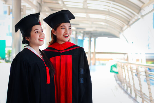 Portrait Of Two Happy Smiling Graduated Students, Young Beautiful Asian Women Looking At Same Way, So Proud On Their Commencement Day, People Celebrating Successful Education On Graduation Day When Ha