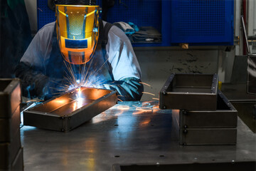 Professional welder performs work with metal parts in factory, sparks and electricity. Industry worker banner.