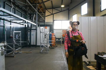 a portrait of a women welder holding a helmet and preparing for a working day in the metal industry