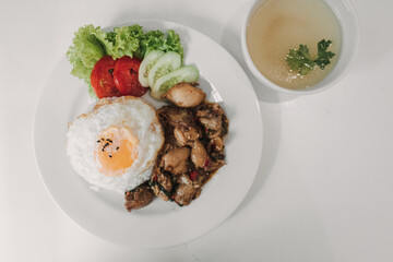 Rice with Basil Fried Chicken and fried egg served on white table.