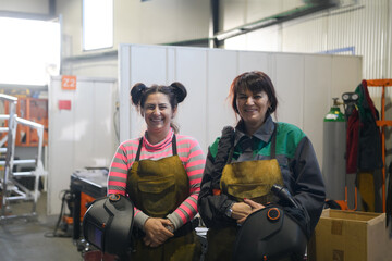 portrait of two welders holding welding masks in their hands and preparing for hard work in a factory