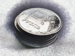 Translation of the inscription: ruble. Stack of Russian coins. Above there is a 1 ruble coin with...