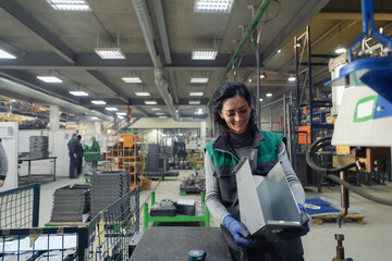 a woman working in a modern metal factory assembles parts for a new machine