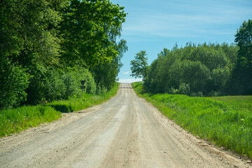 Fototapeta na wymiar endless beautiful country gravel road in perspective with dust and sun rays above. travel the future