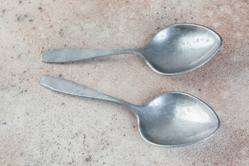 Huge aluminum spoons on concrete background.