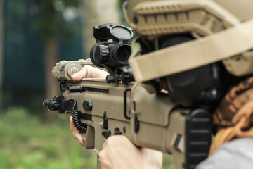 Shooter aiming assault rifle at target.