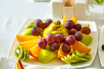 a plate of fruit on a banquet table with a white tablecloth.