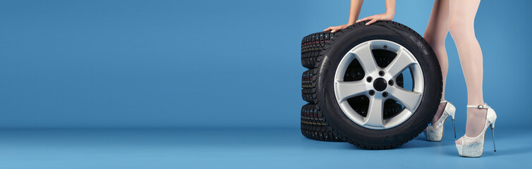 set of studded wheels and beautiful female legs on a blue background with copy space. banner for tire service. tire shop advertisement. set of winter wheels on a blue background 