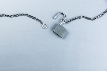 unlocked padlock with chain on gray concrete background with copy space