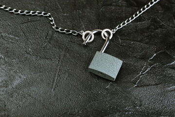 Fototapeta na wymiar unlocked padlock with chain on black concrete background with copy space