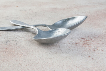 Huge aluminum spoons on concrete background.