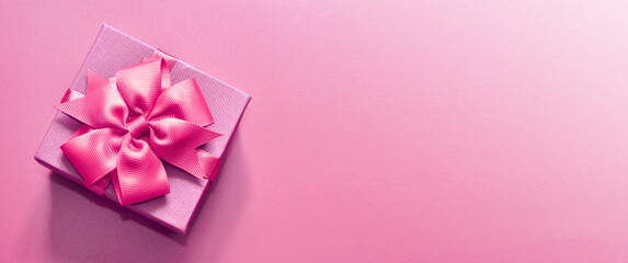 Holiday concept banner with hand made gift box, bow on a purple background with space for text.